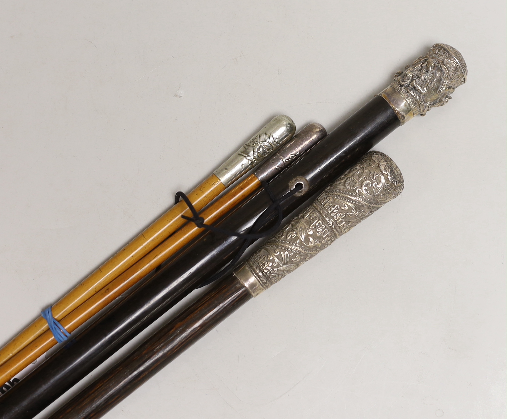 Two Indian embossed silver tipped walking sticks and two Burmese police swagger sticks (4)